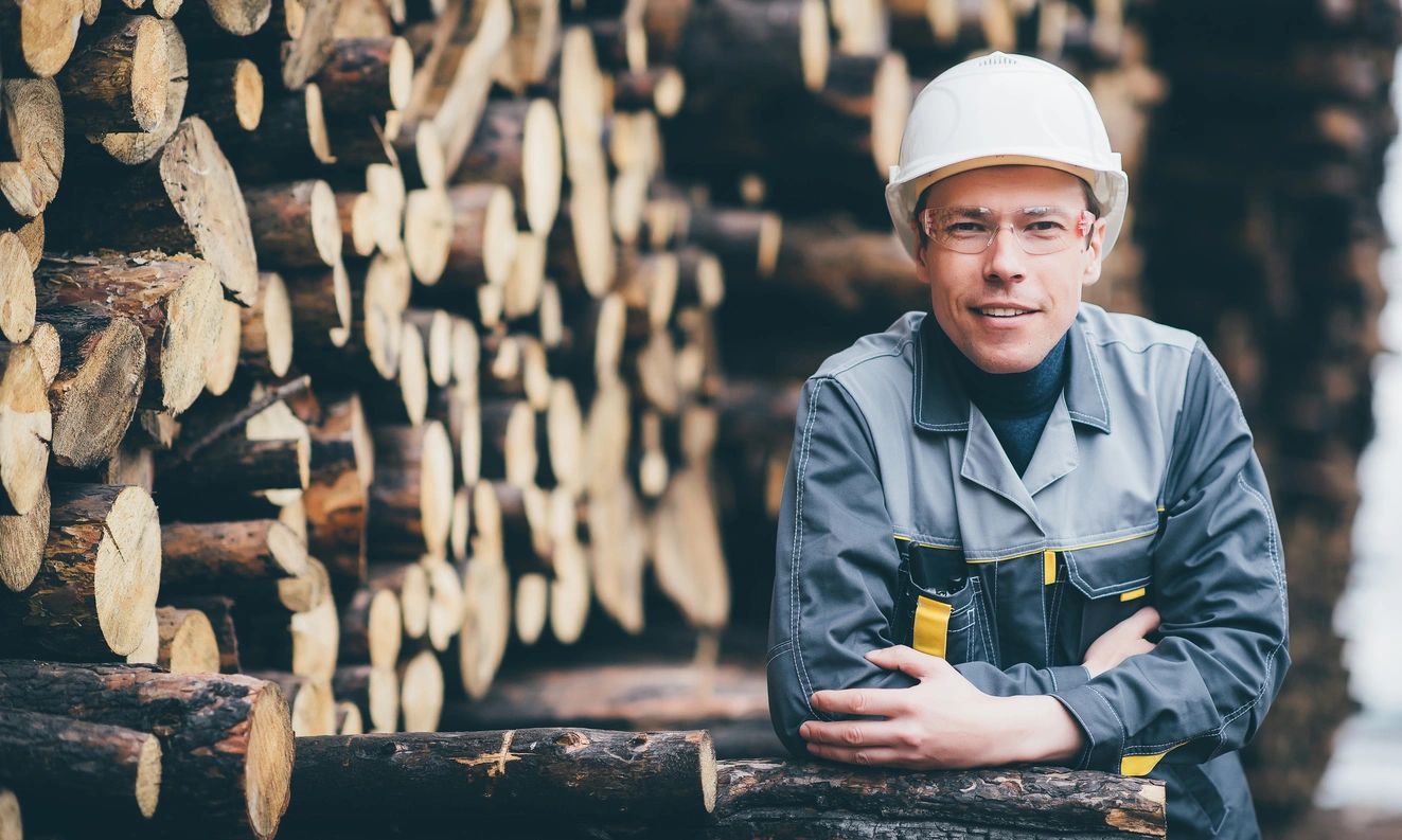 A man in a hard hat sitting on top of a pile of wood.